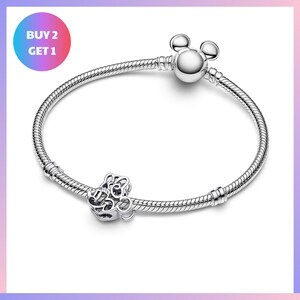 A silver bracelet with a charm and a tag, along with a promotional message for a buy-two-get-one offer.