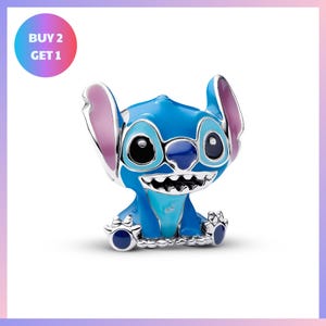 A blue plush toy resembling the character Stitch from the Disney movie "Lilo & Stitch". The toy has a smiling expression and is sitting on the ground.