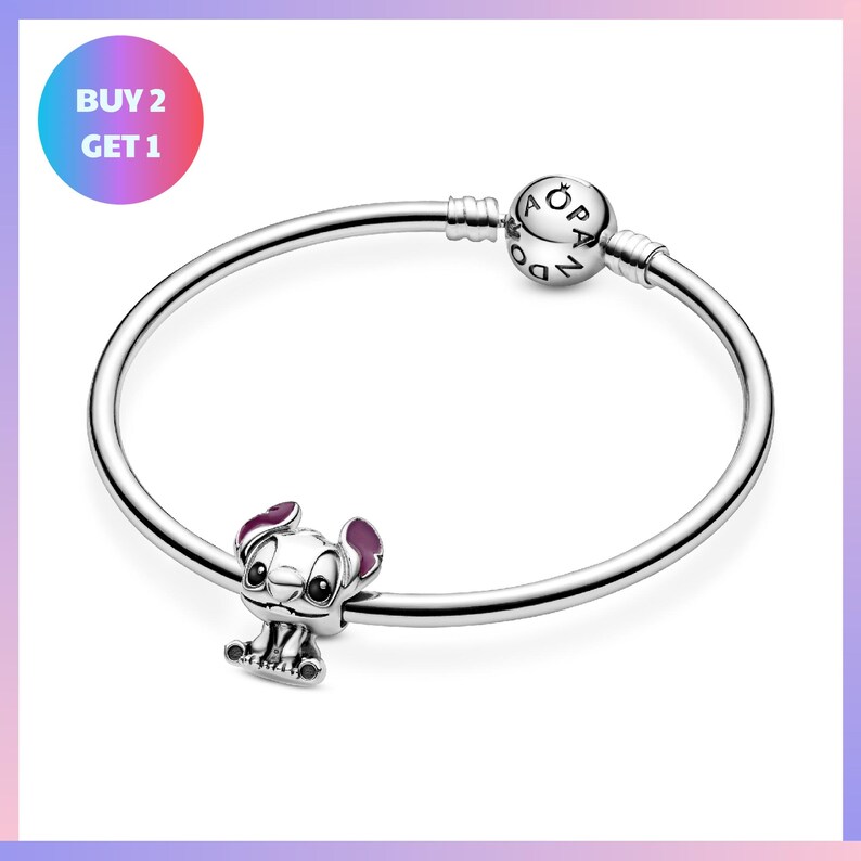 a silver bracelet with a charm in the shape of a cartoon character, specifically a dog. The charm is attached to the bracelet with a loop, and there is a text overlay that reads "BUY 2 GET 1".