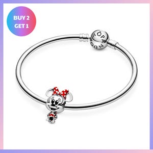 a silver bracelet with a charm in the shape of Minnie Mouse, and there is a promotional message for a buy-two-get-one offer.
