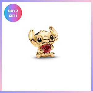 A gold-colored charm in the shape of a cartoon character holding a heart-shaped gemstone.