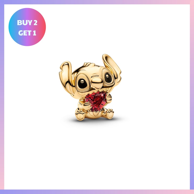 A gold-colored charm in the shape of a cartoon character holding a heart-shaped gemstone.