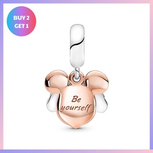 A charm in the shape of a pair of ears, with the text "Be yourself" engraved on it.