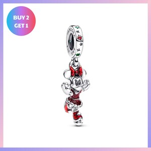 A silver charm in the shape of Minnie Mouse, wearing a red dress, is displayed against a white background.