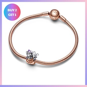 a copper-colored charm bracelet with a small mouse charm and a pumpkin charm. The bracelet has a twisted metal design and is displayed against a white background.