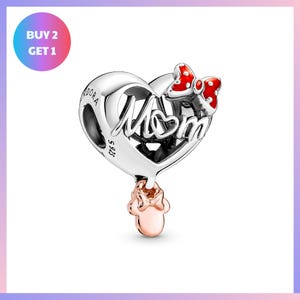a silver heart-shaped pendant with the word "Mom" written on it, along with a red bow charm. The pendant is displayed against a white background, and there is a promotional offer for the purchase of two pieces of the same item.