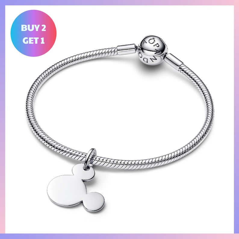 A silver-colored bracelet with a charm featuring the iconic Mickey Mouse logo, and a text overlay that says "BUY 2 GET 1".