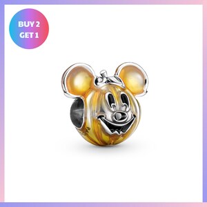 A silver and gold charm in the shape of a smiling face, resembling a character from Disney or a similar popular character.