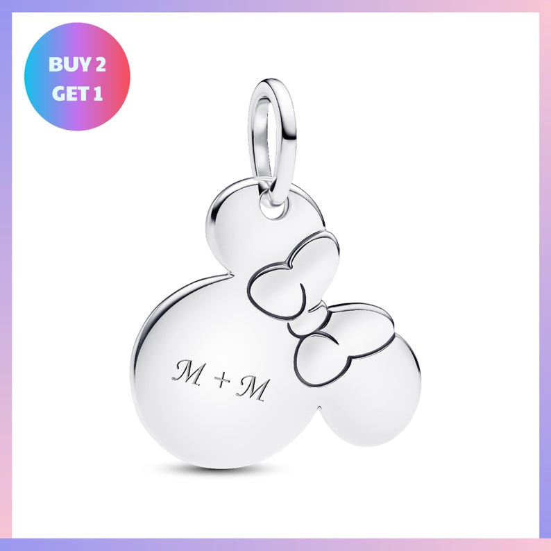 A silver charm in the shape of a Mickey Mouse with a bow tie, and the text "M + M" engraved on it.