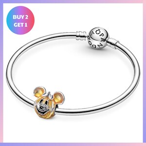a silver bracelet with a charm in the shape of a cartoon character, specifically a Mickey Mouse. The bracelet has a silver bead and a charm in the shape of a ball.