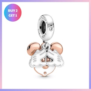 a pendant charm in the shape of a cartoon mouse with a heart-shaped tag attached to it.