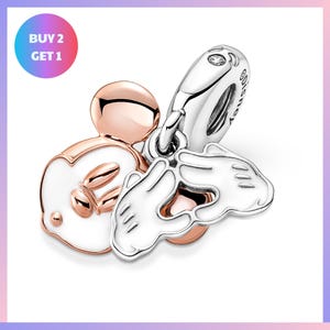 a collection of charms, including a Mickey Mouse charm, a pair of white hand charms, and a silver charm.