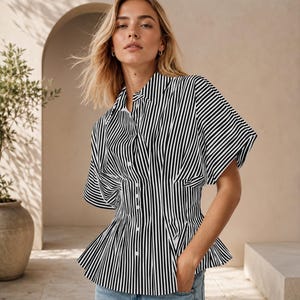 May include: A short-sleeved button-down shirt featuring a vertical black and white striped pattern. The garment has a structured, cinched waistline with pleats that create a flared peplum hem, a classic collar, and a front button closure.