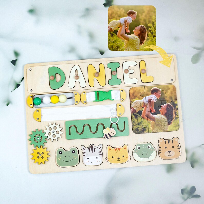 May include: Wooden activity board with the name "DANIEL" in yellow and green letters. Features include a puzzle, gears, beads, a buckle, a zipper, and animal shapes. Includes a photo of a mother and child.