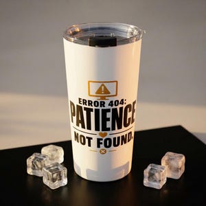 May include: A white insulated tumbler with a clear lid. The tumbler features the text "ERROR 404: PATIENCE NOT FOUND" in black and gold. The design includes a computer monitor icon and a heart symbol. Several ice cubes are in front of the tumbler.