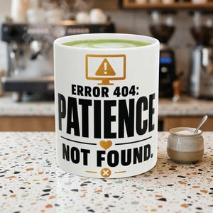 May include: White ceramic mug filled with green liquid, with the text "ERROR 404: PATIENCE NOT FOUND." The mug has a gold computer screen icon with an exclamation mark. A small ceramic container with a spoon is next to the mug.