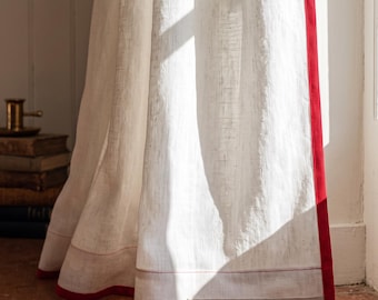 May include: A white linen curtain panel featuring a vibrant raspberry red border trim along the vertical edge and bottom hem. A small rectangular label at the bottom reads: Pure White Linen - Trimmed in Raspberry Red. The fabric has a visible weave.