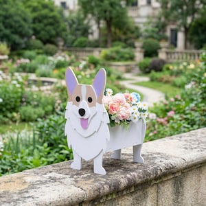 May include: A white, tan and lavender wooden planter shaped like a Corgi dog. The front panel features the dog's face with a pink tongue, while the attached rectangular container holds a bouquet of artificial pink, white and blue flowers.