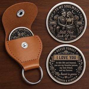 May include: A tan leather keychain pouch with a snap closure containing a round metal coin. Two round metal coins are displayed, one featuring a skeleton couple with the text TO MY SOULMATE, DANIEL, EMMA, and Still Not Sick Of You. The other coin reads NEVER FORGET I LOVE YOU.