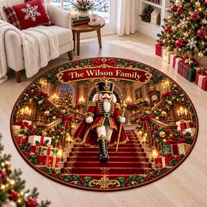 May include: A round Christmas-themed area rug featuring a nutcracker in a red and gold uniform standing on a red carpeted staircase. The design includes a banner with the text The Wilson Family, surrounded by garlands, gifts, and lights.