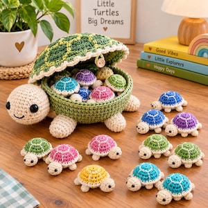 May include: A large crocheted turtle container with a removable shell lid, filled with several smaller crocheted turtles in various colors including blue, purple, pink, green, and yellow. The large turtle has a cream-colored head and limbs.