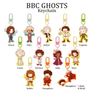 Könnte beinhalten: Eine Sammlung von BBC Ghosts-Charakter-Schlüsselanhängern. Jeder Schlüsselanhänger zeigt eine farbenfrohe Cartoon-Illustration eines Charakters, mit Namen wie Alison, Mike, Julian, Pat, Captain, Fanny, Thomas, Kitty, Mary, Robin und Humphrey.