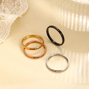 Può includere: Quattro anelli sottili in metallo nei toni dell'oro, oro rosa, nero e argento. L'anello dorato è inciso con il nome Amelia, l'anello in oro rosa con Rialto, l'anello nero con Isla e l'anello argentato con il nome Lily in un carattere semplice.