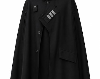 May include: A black hooded cape featuring a front button closure, a small rectangular chest pocket with three silver-toned reflective stripes, and a larger flap pocket on the lower left side. The garment has a structured hood and arm slits.