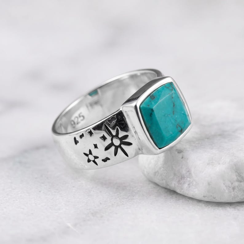 Peut inclure: Une bague en argent sterling orn&eacute;e d'une pierre turquoise de taille carr&eacute;e et de motifs d'&eacute;toiles grav&eacute;s sur l'anneau. L'int&eacute;rieur de l'anneau porte clairement le poin&ccedil;on 925, indiquant la teneur en argent de ce bijou en m&eacute;tal poli.