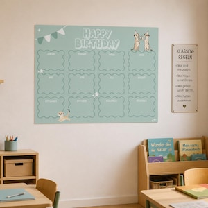 May include: A sage green rectangular birthday calendar wall poster featuring the text "HAPPY BIRTHDAY," twelve scalloped monthly boxes, illustrations of meerkats, and white bunting accents. The poster is displayed on a plain wall.