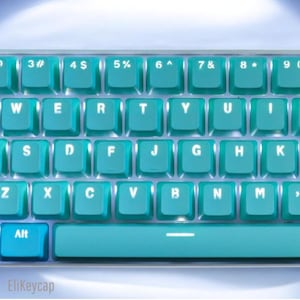 Peut inclure: Un clavier mécanique avec des touches bleu sarcelle et des lettres blanches. La disposition comprend les touches QWERTY standard, des chiffres et des symboles. La rangée inférieure inclut une touche Alt et une longue barre d'espace. EliKeycap est visible.