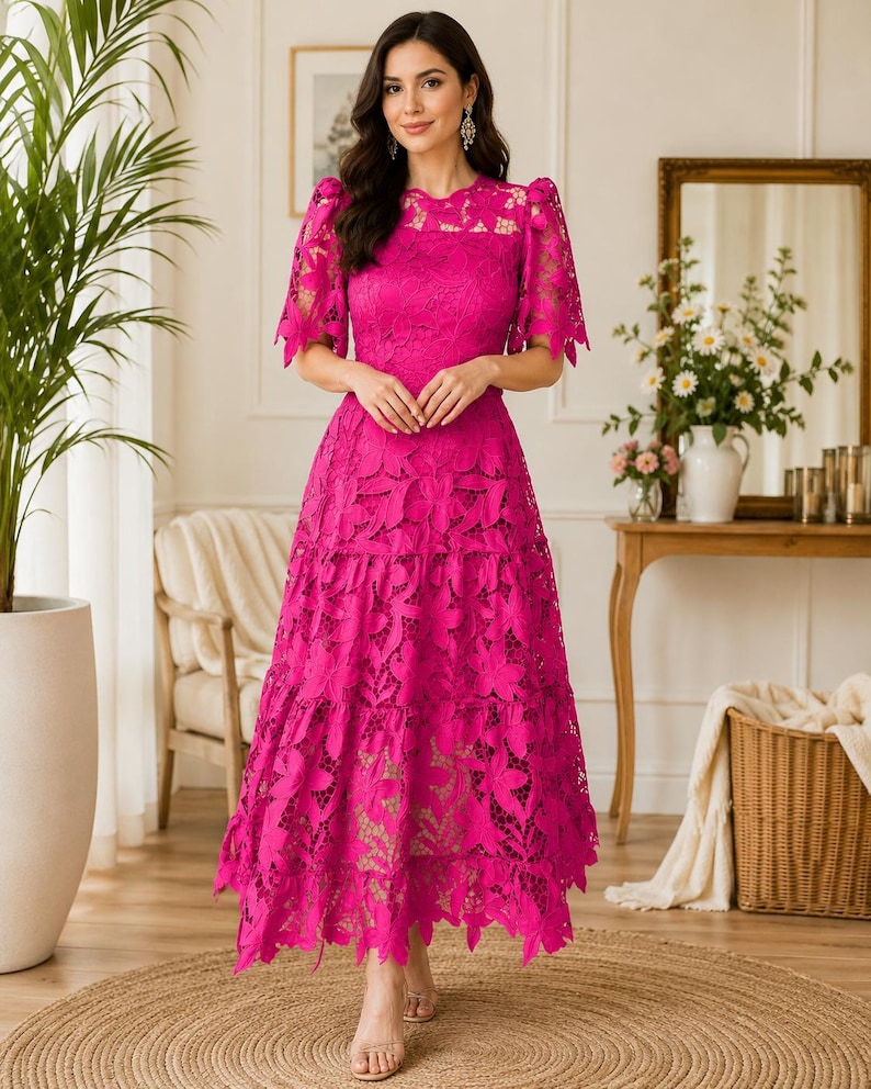 May include: A vibrant fuchsia midi dress featuring intricate floral lace detailing, short puff sleeves, a round neckline, and a tiered skirt with a scalloped hemline. The garment is constructed with a solid-colored lining beneath the lace overlay.