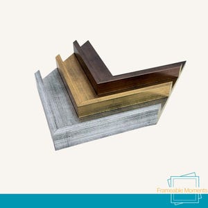 May include: Four wooden picture frame corners in silver, gold, brown, and dark brown. The frames are stacked, showcasing the different colours and textures. The bottom right corner of the image has the text "Frameable Moments".