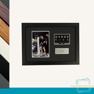 May include: A black framed photo collage featuring a sports event. The collage includes a photo of athletes, the text "HYROX RIGA", and a small plaque that reads "My First Hyrox Riga 2023".