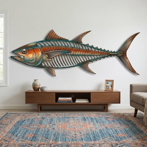 Peut inclure: Une grande sculpture murale en métal représentant un thon. Le poisson présente un design de cage thoracique squelettique avec un dégradé de tons métalliques bleu, orange et cuivre. Les nageoires et la queue sont pointues et le corps est détaillé.