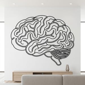 Op de afbeelding: Een zwarte omtrek van een menselijk brein, bevestigd aan een witte muur. De ingewikkelde windingen van de hersenen zijn duidelijk gedefinieerd. Een modern, minimalistisch kunstwerk, geschikt voor thuis of op kantoor.