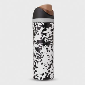 May include: A cylindrical water bottle featuring a white base with an irregular black splatter pattern. The top section consists of a grey band, a black cap, and a brown flip-top lid. The bottle has a smooth, straight-sided design throughout.