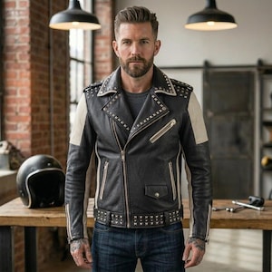 May include: A black leather motorcycle jacket with cream-colored side panels and sleeves. The jacket features silver metal studs along the lapels, shoulders, and waist belt, with a diagonal front zipper, zippered pockets, and a small flap pocket.