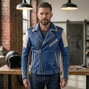 Könnte beinhalten: Eine blaue Motorradjacke aus Leder mit beigen Seiteneinsätzen, silberfarbenen Metallnieten an Revers, Schultern und Saum, einem diagonalen Frontreißverschluss, mehreren Reißverschlusstaschen und einer kleinen Pattentasche auf der Brust.