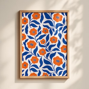 Può includere: Un'opera d'arte da parete rettangolare incorniciata con un motivo ripetuto di fiori arancioni vivaci con centri blu scuro e foglie blu scuro stilizzate su uno sfondo bianco, racchiusa in una semplice cornice in legno di tonalità chiara.