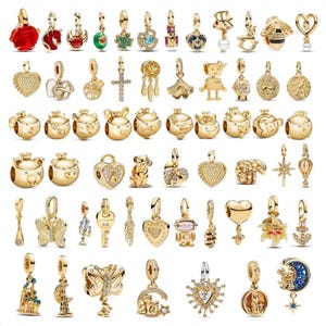 Könnte beinhalten: Eine Sammlung goldfarbener Charms und Anhänger mit verschiedenen Designs wie Herzen, Tieren, Schmetterlingen und Himmelsmotiven. Einige Charms sind mit Edelsteinen verziert. Die Charms sind für Armbänder oder Halsketten konzipiert.