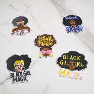 Puede incluir: Cinco parches bordados con ilustraciones estilizadas de mujeres negras con diversos peinados y accesorios. Los parches incluyen textos como Brown skinned GIRL, Black Girl Magic y BLACK GIRL MAGIC en diversas fuentes, colores y estilos de bordado.