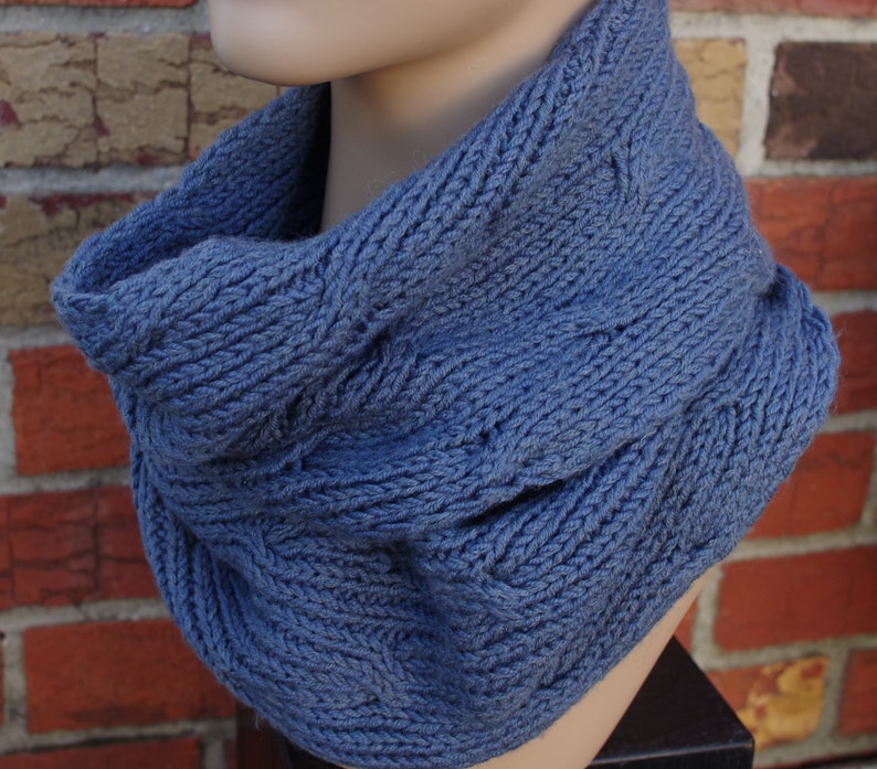 May include: A blue knitted neck warmer with a cable knit pattern.