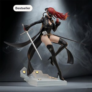 May include: A detailed figurine of a character in a black outfit, holding a sword and a small red object. The figure has red hair and a mask. The base is white with yellow lights. The word "Bestseller" is in a white oval in the top left corner.