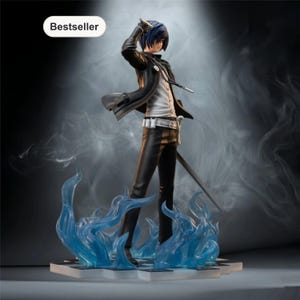May include: A detailed figurine of a character in a black jacket, white shirt, and black pants, holding a sword. The figure has blue hair and stands on a base with blue flame accents. The word "Bestseller" is in a white oval in the upper left corner.