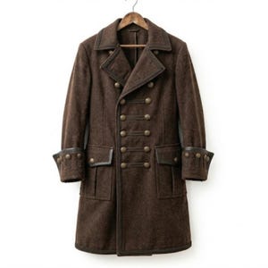 Può includere: Un cappotto marrone scuro lungo fino al ginocchio con chiusura a doppio petto e due file di bottoni metallici rotondi. Il capo presenta ampi revers, due tasche con patta in vita e polsini decorati con una fila di bottoni abbinati.