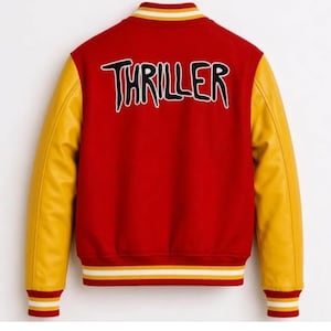 Puede incluir: Una chaqueta universitaria roja con mangas amarillas y la palabra THRILLER bordada en negro con un borde blanco en la espalda. La chaqueta presenta un cuello, pu&ntilde;os y dobladillo acanalados con rayas amarillas y blancas de dise&ntilde;o deportivo.