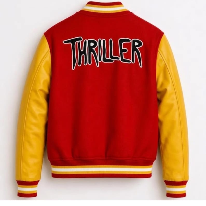 Puede incluir: Una chaqueta universitaria roja con mangas amarillas y la palabra THRILLER bordada en negro con un borde blanco en la espalda. La chaqueta presenta un cuello, pu&ntilde;os y dobladillo acanalados con rayas amarillas y blancas de dise&ntilde;o deportivo.