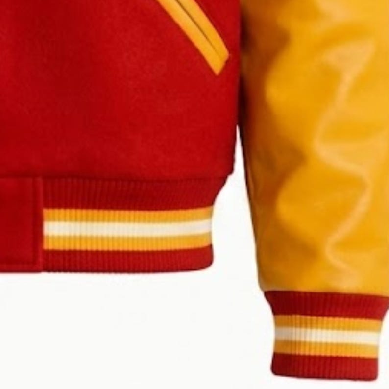 Puede incluir: Una chaqueta universitaria con cuerpo de mezcla de lana roja y mangas amarillas en contraste. La prenda incluye un dobladillo y pu&ntilde;os acanalados con rayas horizontales amarillas y blancas, junto con un bolsillo ribeteado en amarillo al frente.
