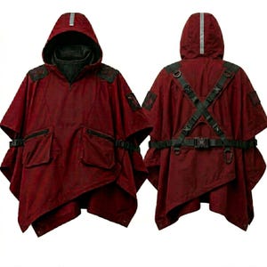 Op de afbeelding: Een bordeauxrode poncho met capuchon en zwarte accenten, met een ritssluiting aan de voorkant, twee voorzakken en verstelbare bandjes. De poncho heeft een reflecterende streep op de capuchon en decoratieve patches op de schouders. De achterkant heeft een kruisbandontwerp.